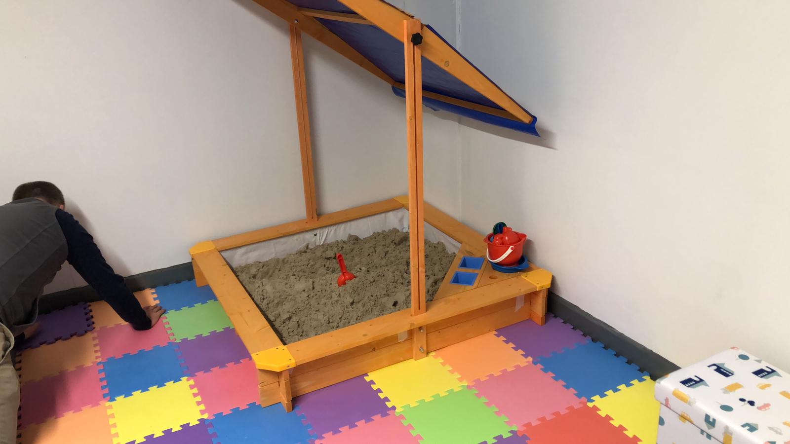 A child is playing in a sandbox in a room. Dramatherapy Ireland