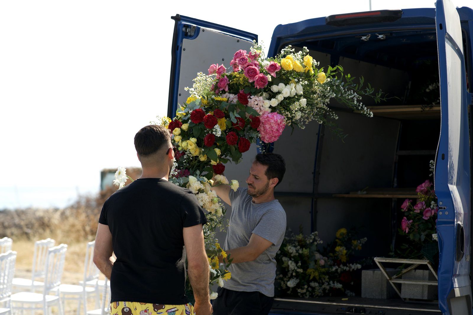 Due persone scaricano una grande composizione floreale dal furgone