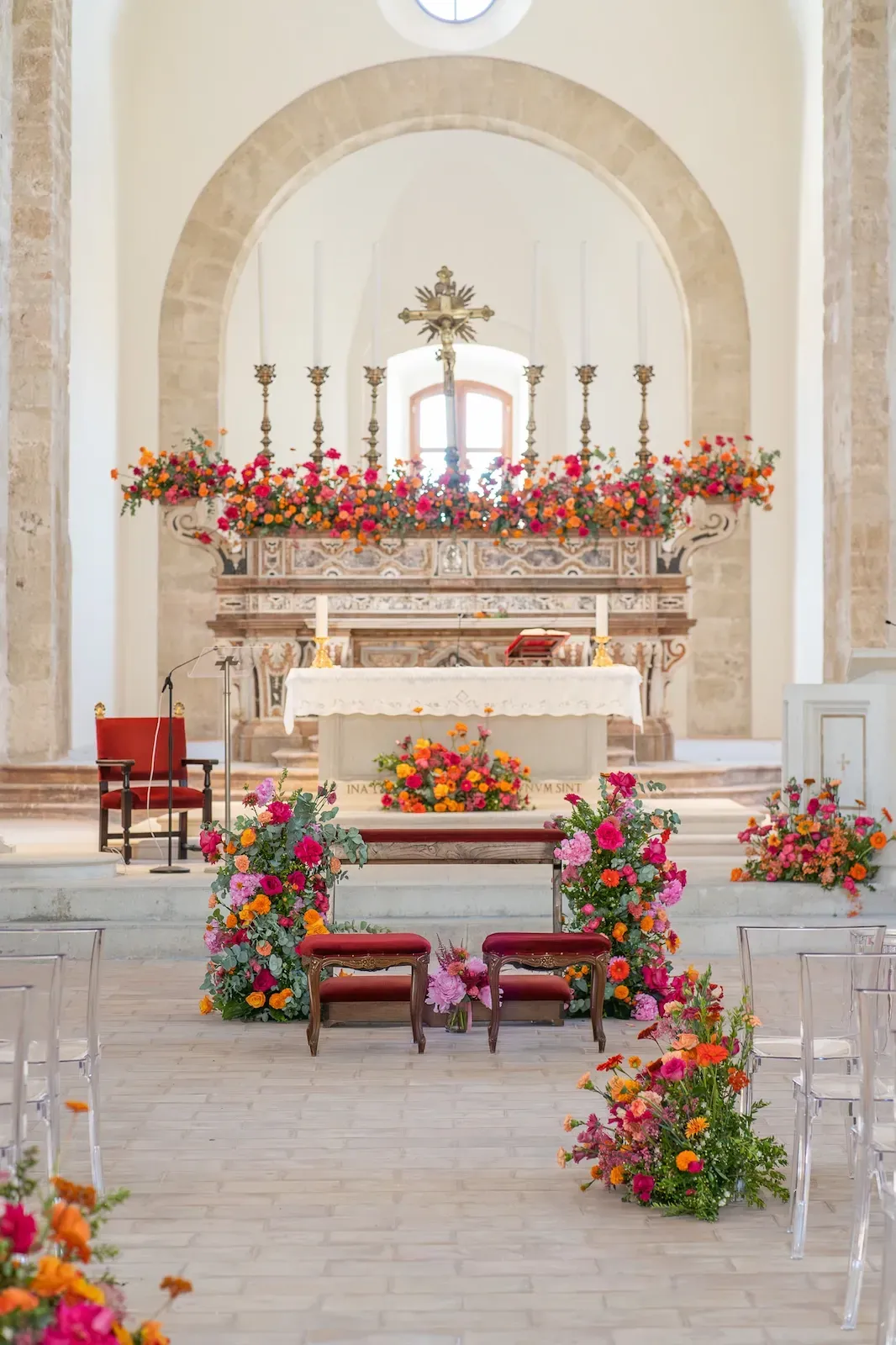 L’allestimento completo: fiori rossi e arancioni sull’altare e composizioni lungo la navata