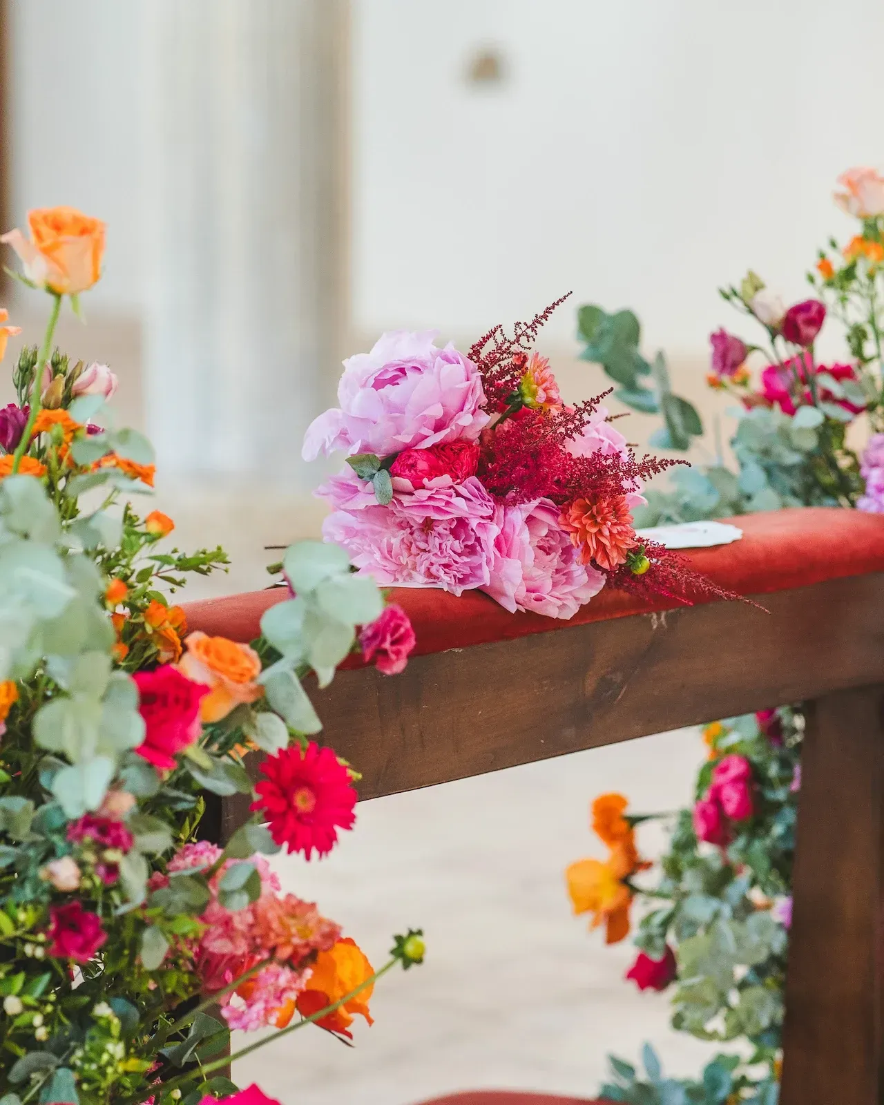Fiori rosa e arancioni fissati alla balaustra in legno di un altare