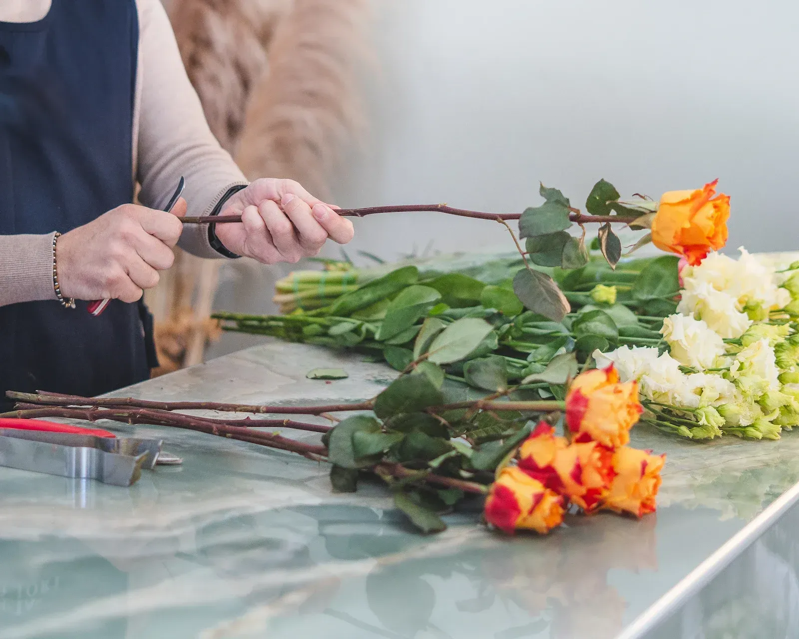 Mani che preparano gli steli delle rose sul banco di lavoro