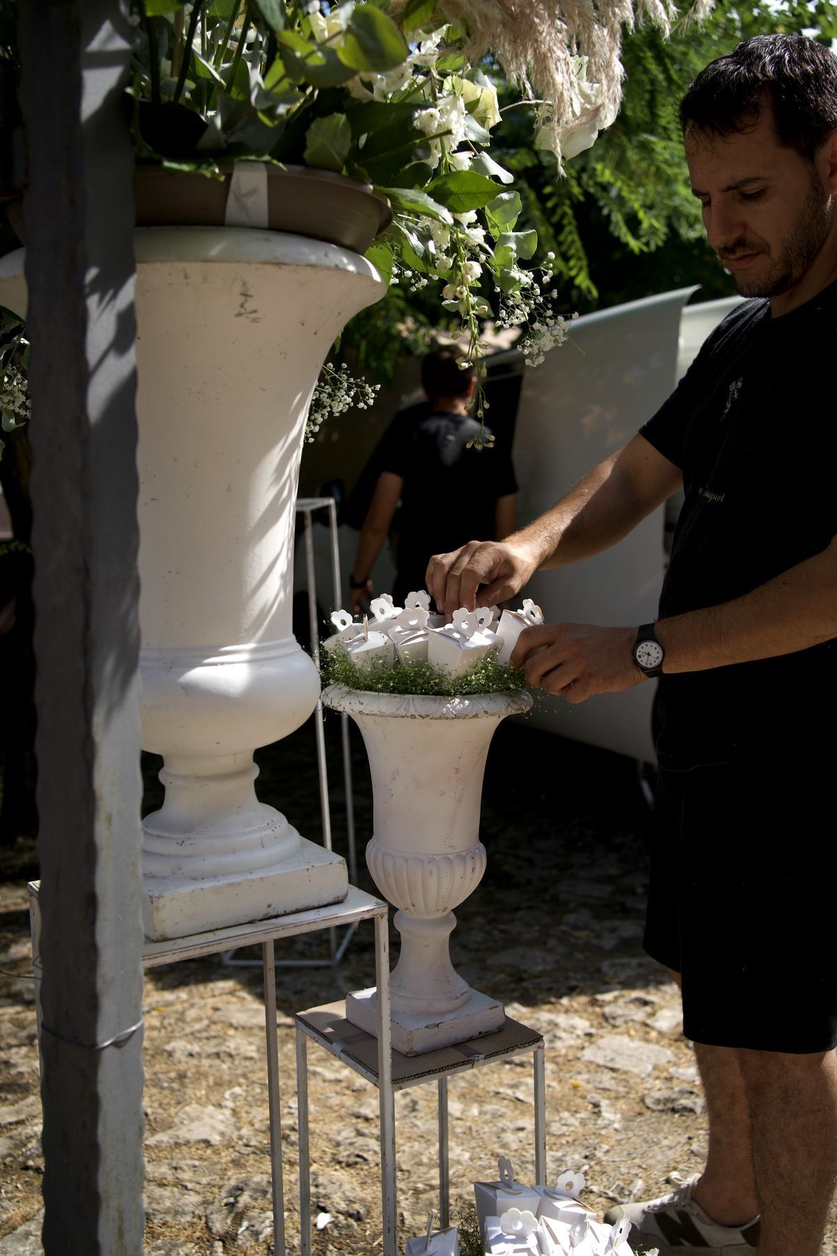 Composizione di fiori bianchi costruita dentro un vaso alto, accanto alla roccia