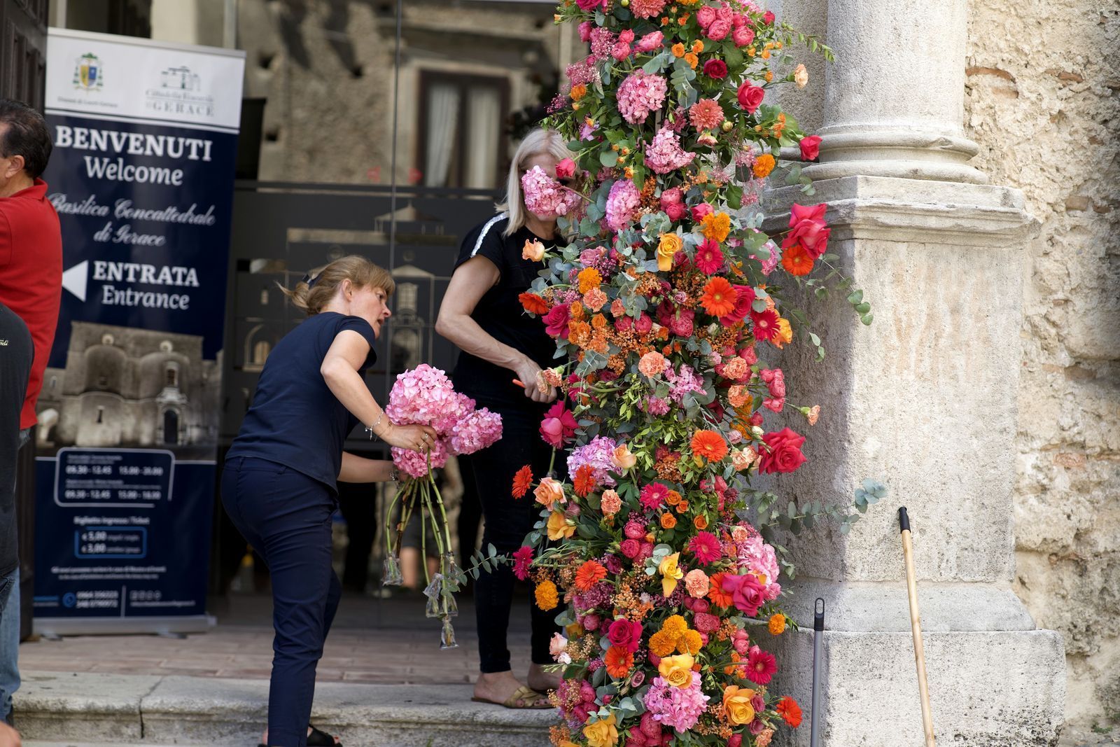 Due persone completano le colonne floreali ai lati del portale