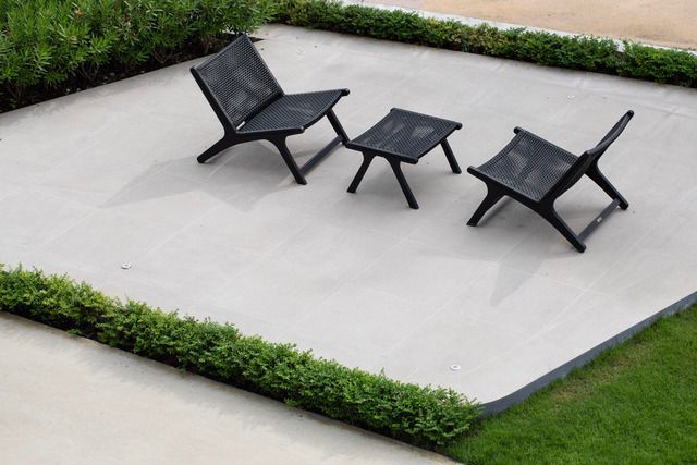 Two chairs and a table are sitting on a concrete patio.