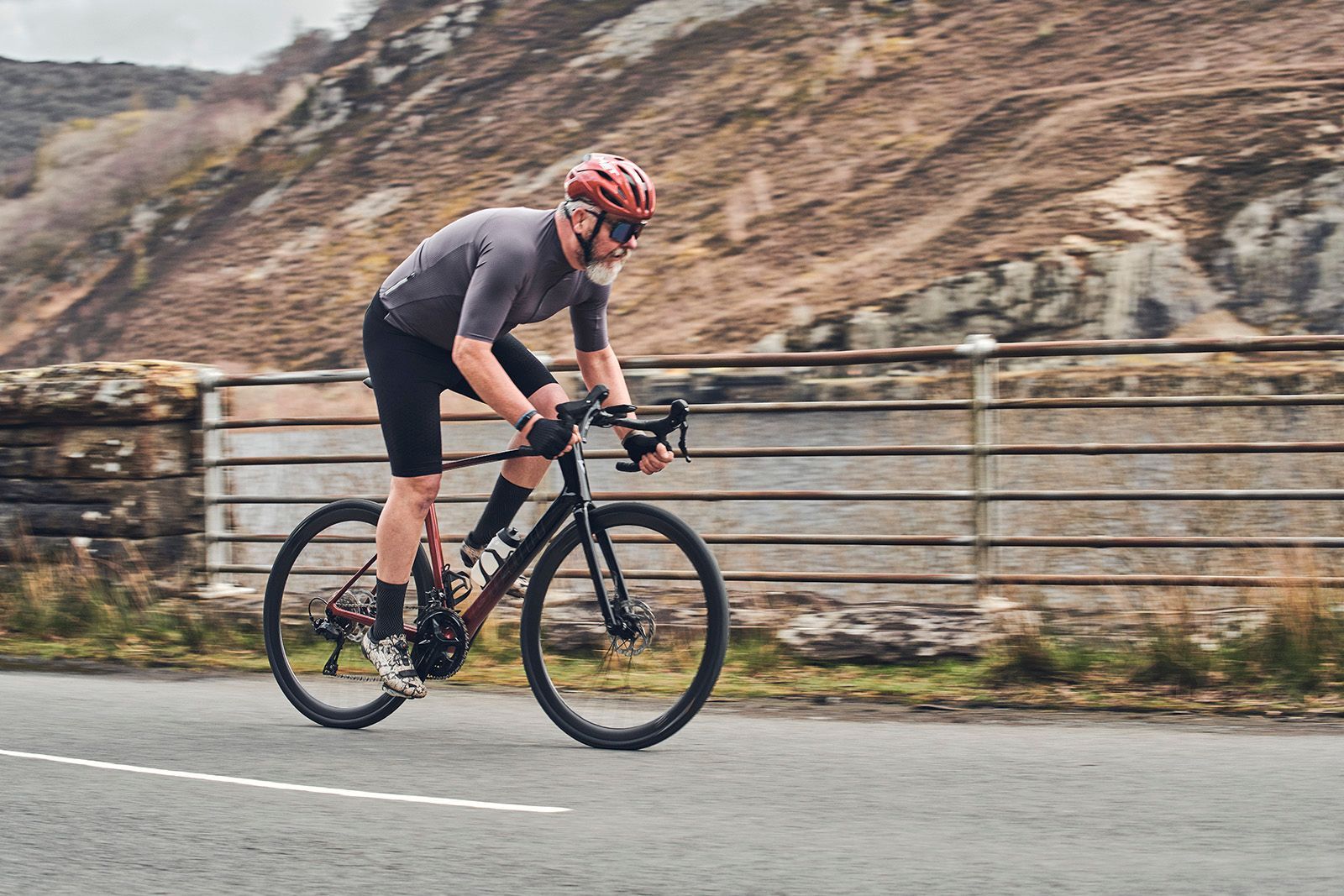 Cyclist in grey and black gear rides a road bike on a mountain road.