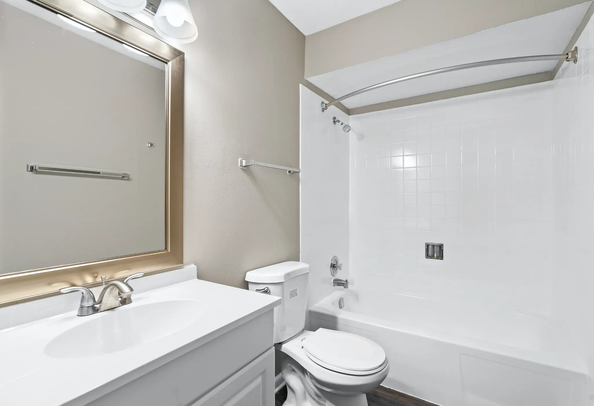 A modern bathroom featuring a bathtub, toilet, and sink with a large mirror.