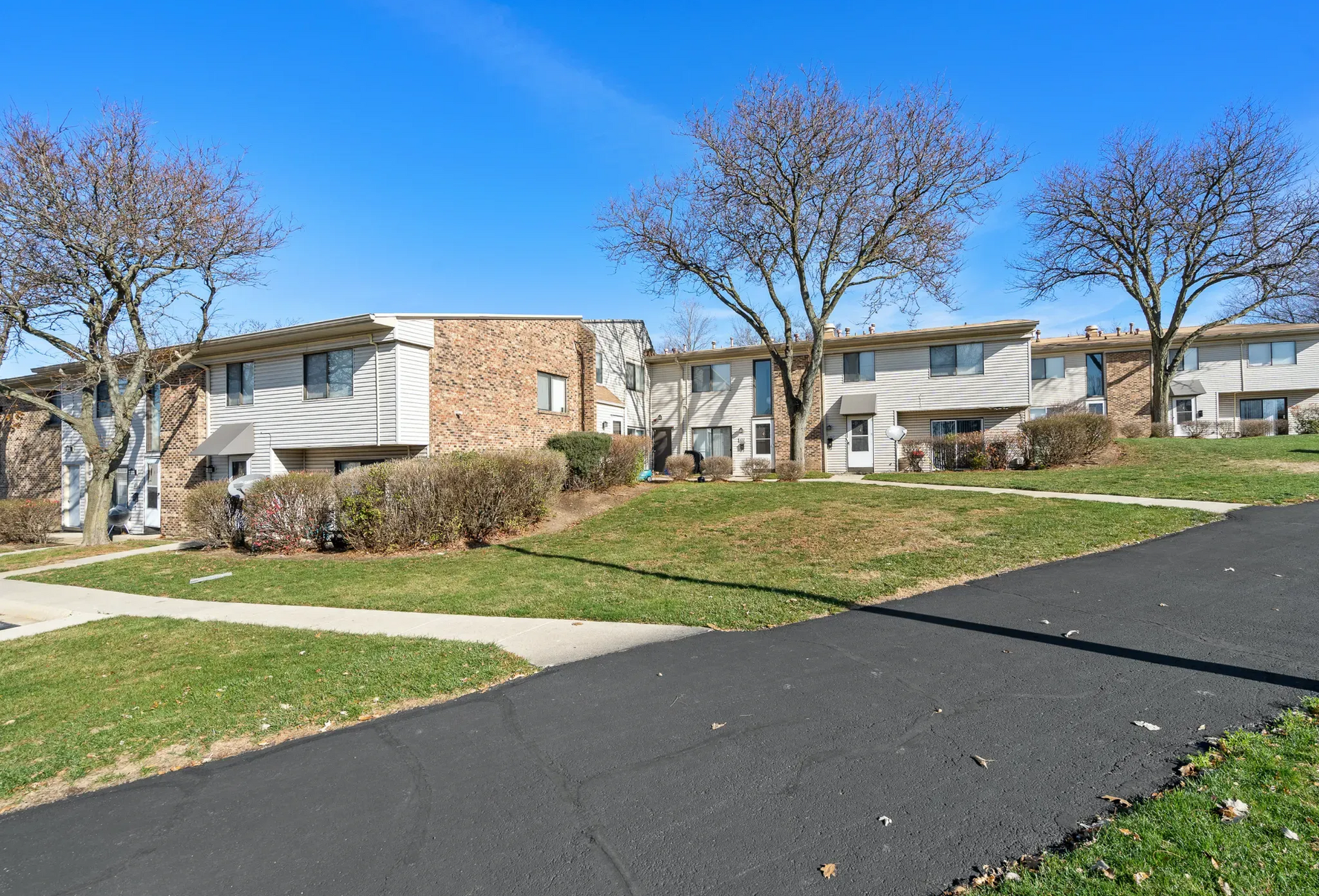 Exterior view of apartment buildings surrounded by grass and trees.