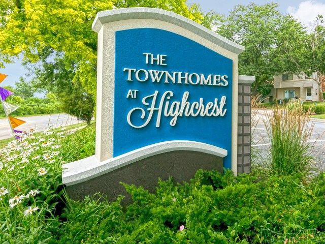 Blue and white monument sign reading The Townhomes at Highcrest at a landscaped entrance.