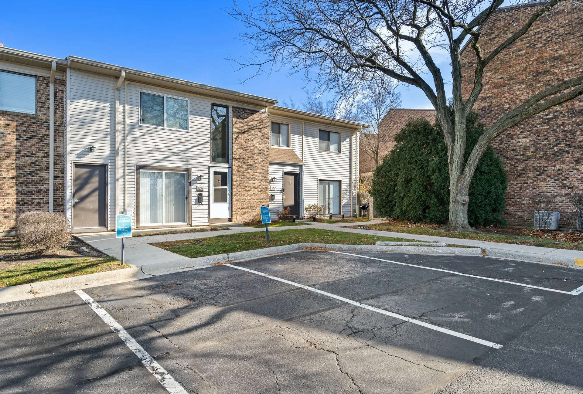 Exterior view of a townhouse-style apartment building row with a parking lot.