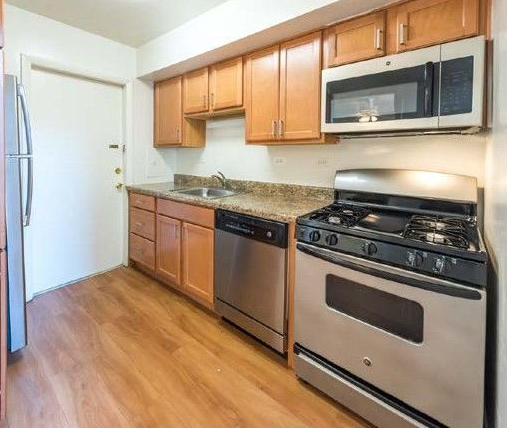 Galley-style kitchen with stainless steel appliances and wooden cabinets.