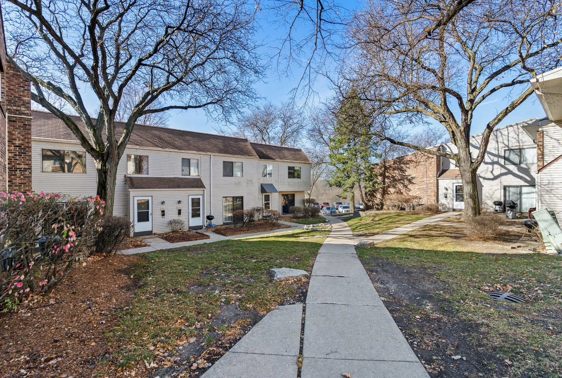 Exterior view of a residential complex with a pathway and trees.