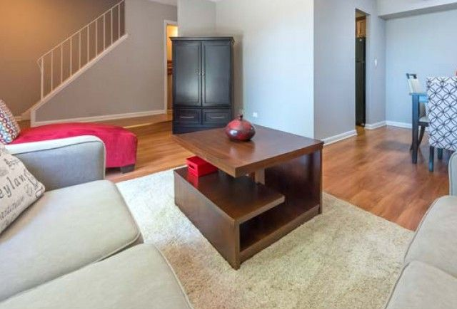 Living room in a modern apartment with gray sofas, a dark wood coffee table, and hardwood floors.