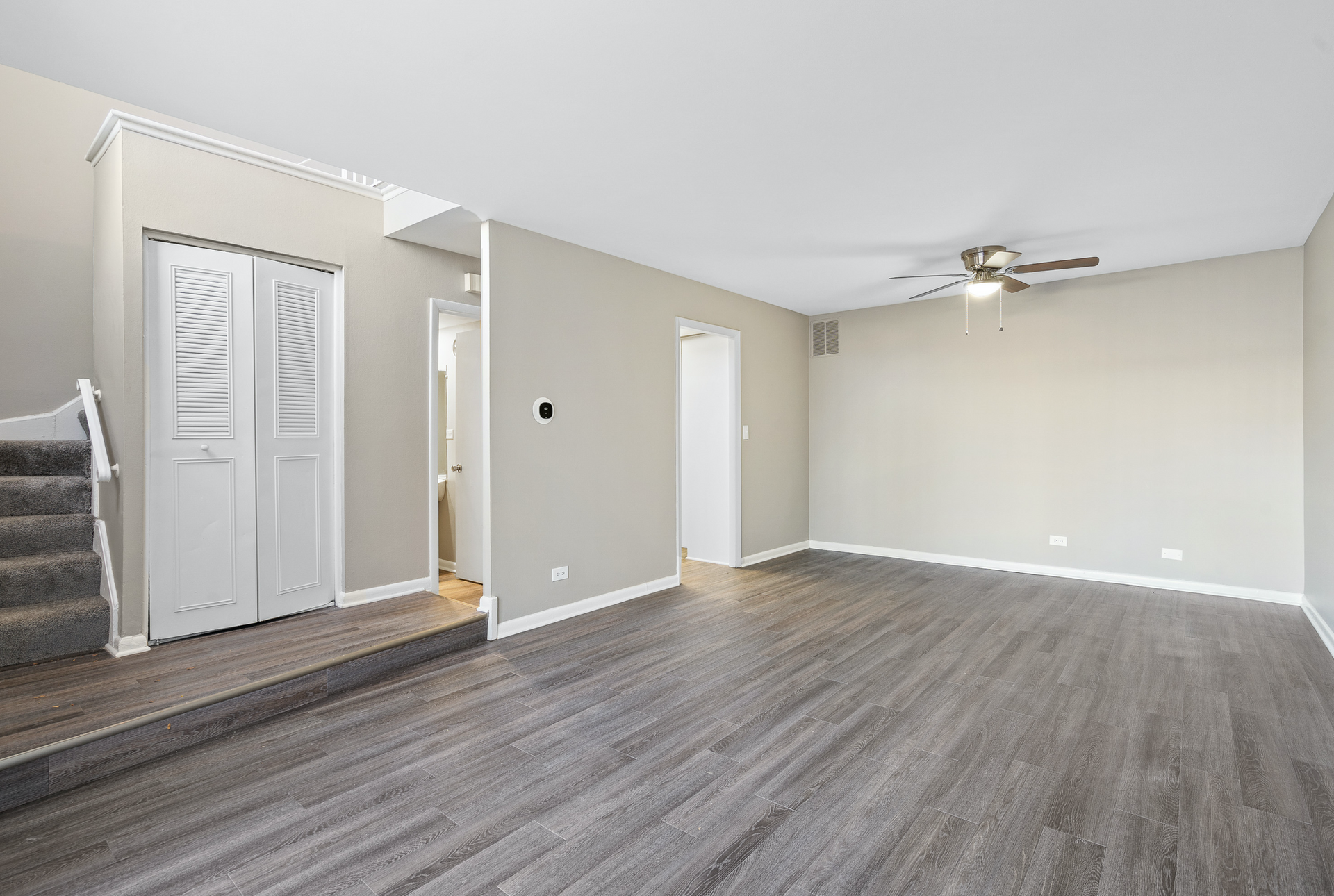 Interior of a finished living area with stairs, gray walls, and a ceiling fan.