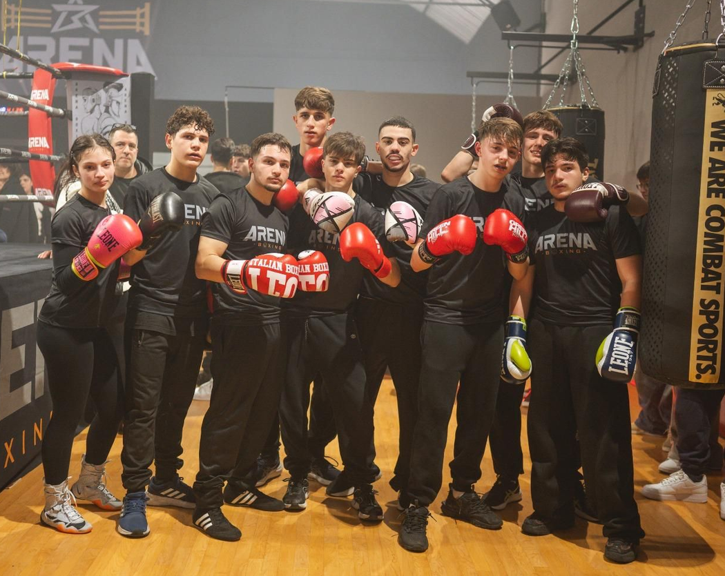 Gruppo di pugili con guantoni rossi in posa in un'area di allenamento in palestra.