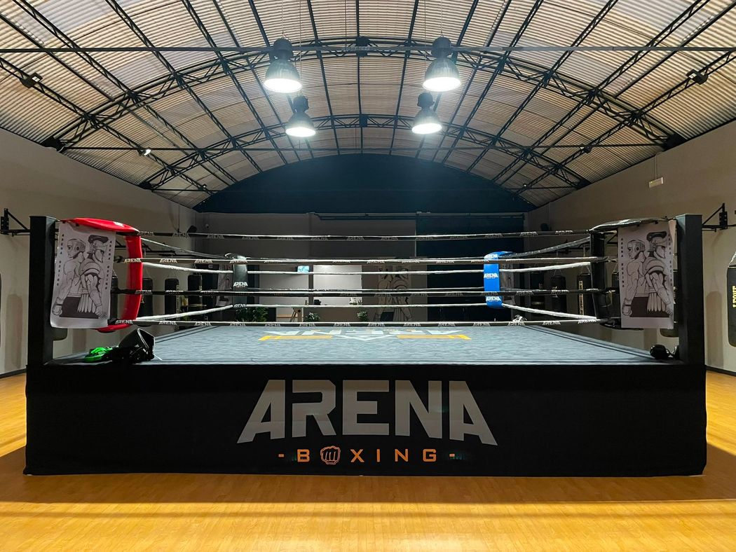Un ring da boxe vuoto all'interno di un'arena al coperto con la scritta
