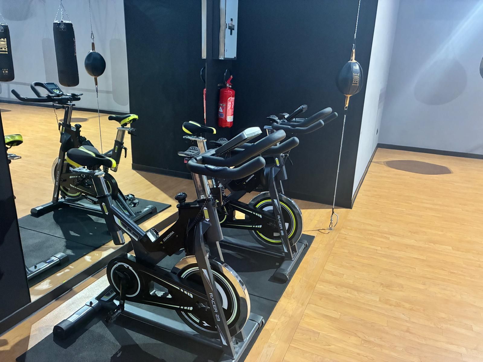 Una fila di monopattini elettrici parcheggiati all'interno, accanto a una parete e a un pavimento in legno.