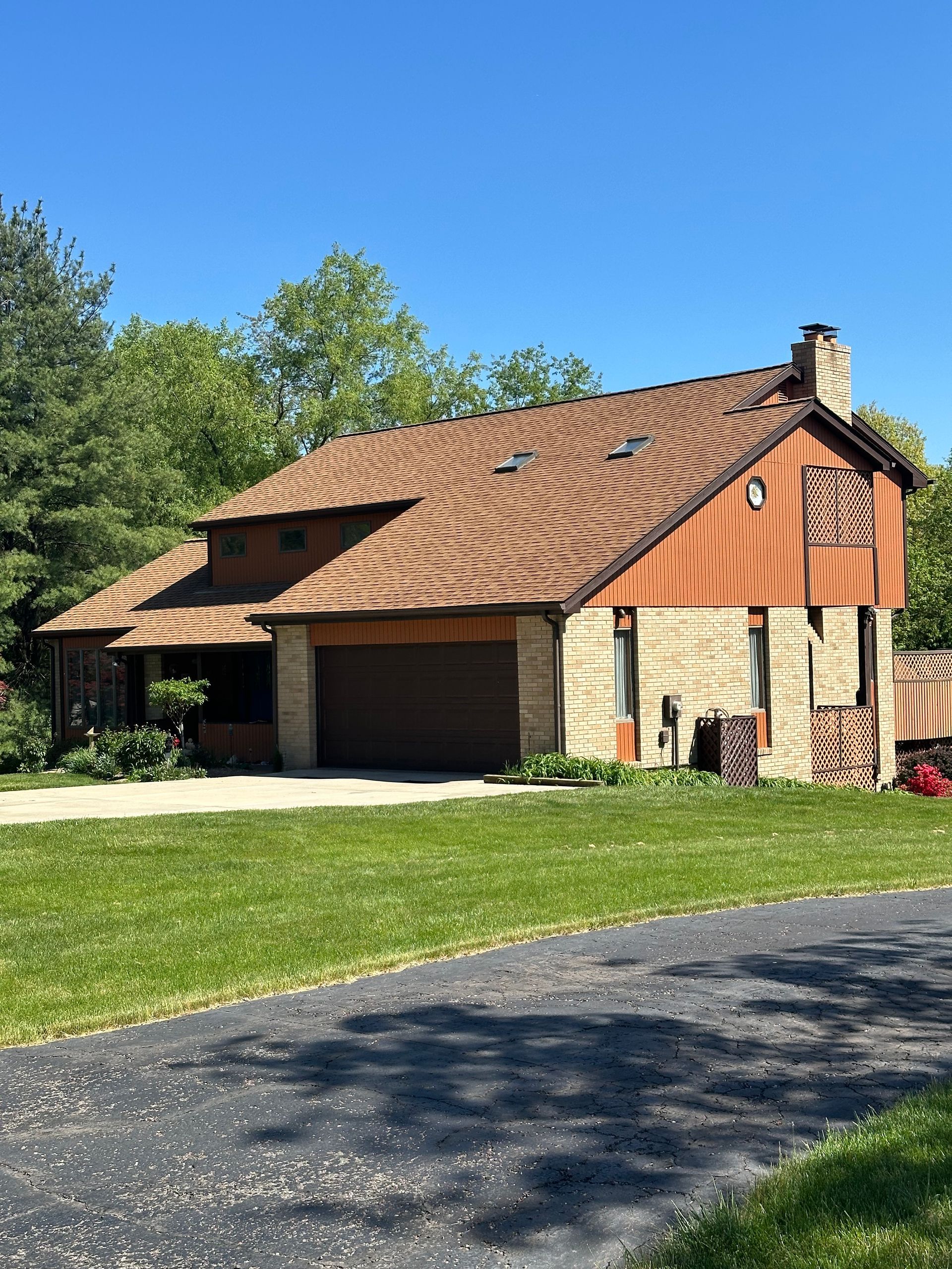 A large house with a brown roof is sitting on top of a lush green field.