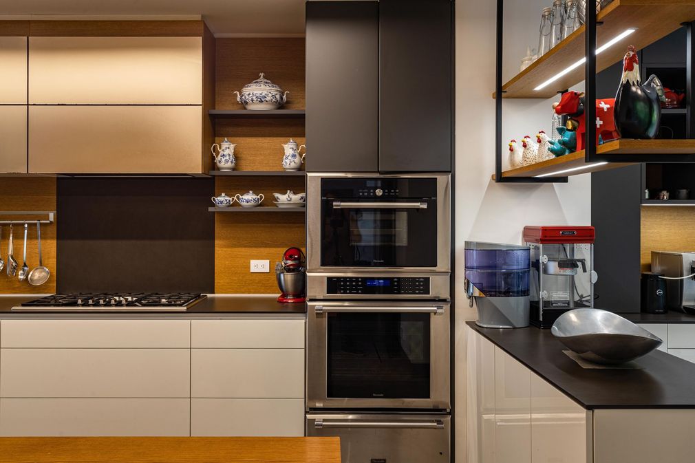 Modern kitchen interior with built-in ovens, open shelves, and black countertops