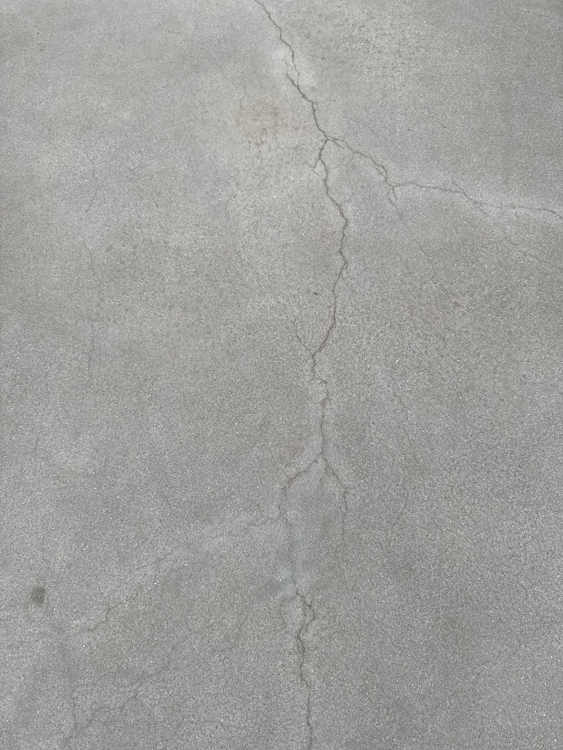 A grey, textured concrete surface with a vertical crack running through the center.