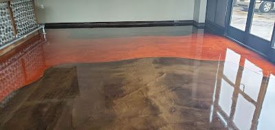 Shiny concrete floor with a swirling, marbled pattern of metallic copper and dark brown tones in an interior space.