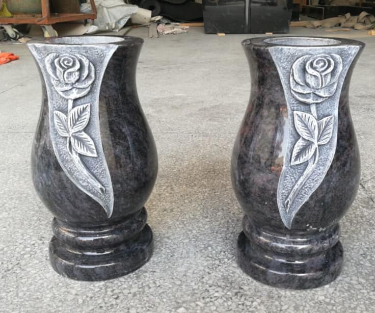 Deux vases en granit sombre ornés de roses sculptées.