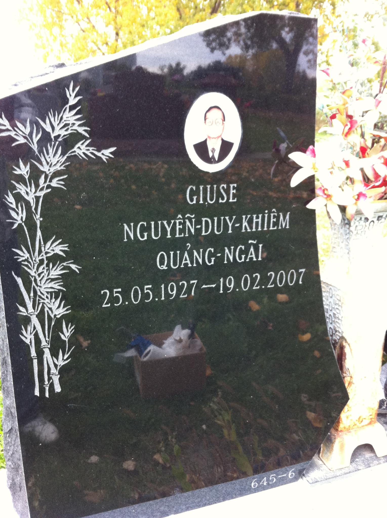 Black headstone with bamboo design, photo, and Vietnamese inscription. Dates: 1927-2007.