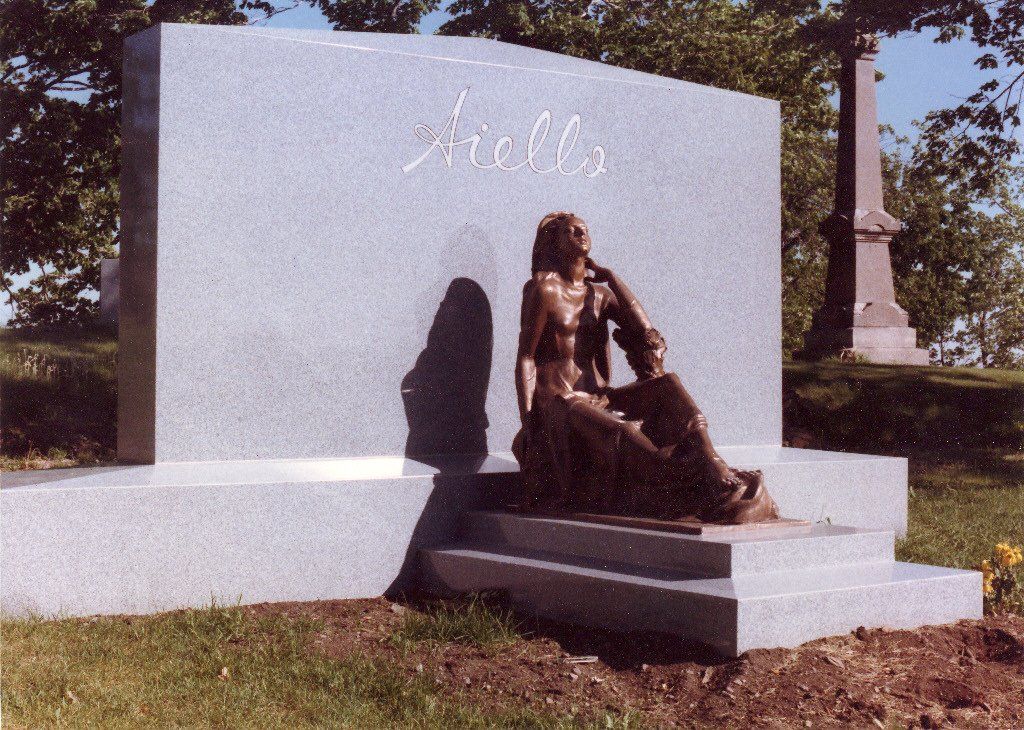 Monument orné de sculptures en bronze représentant des personnages, et portant le nom « Mells » gravé dessus.