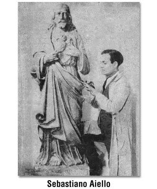 Sculptor Sebastiano Aiello with a statue of a figure draped in robes.