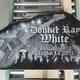 Black granite tombstone engraved with a guitar, name 