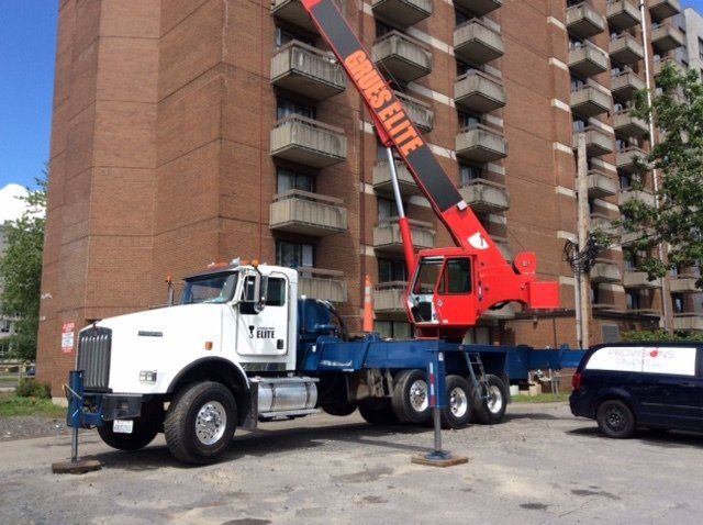 A crane truck is parked in front of a tall building