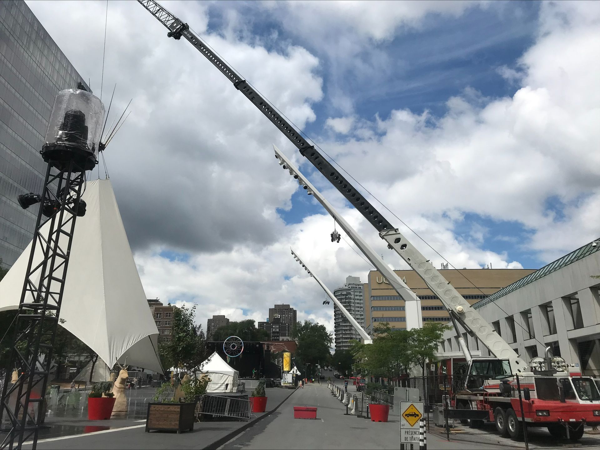 Two large cranes are sitting on the side of a street in front of a building.