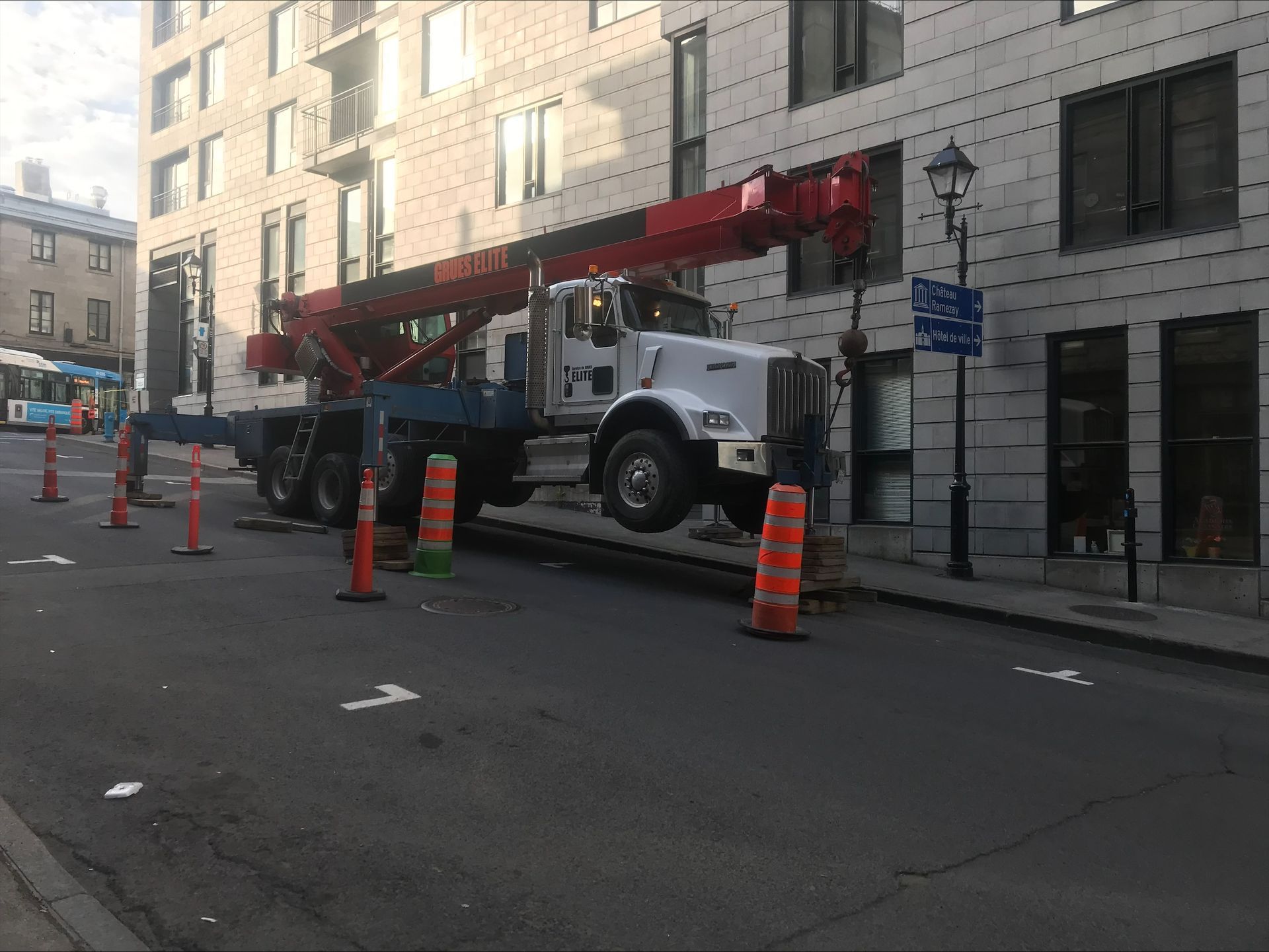 A large crane is parked on the side of the road in front of a building.
