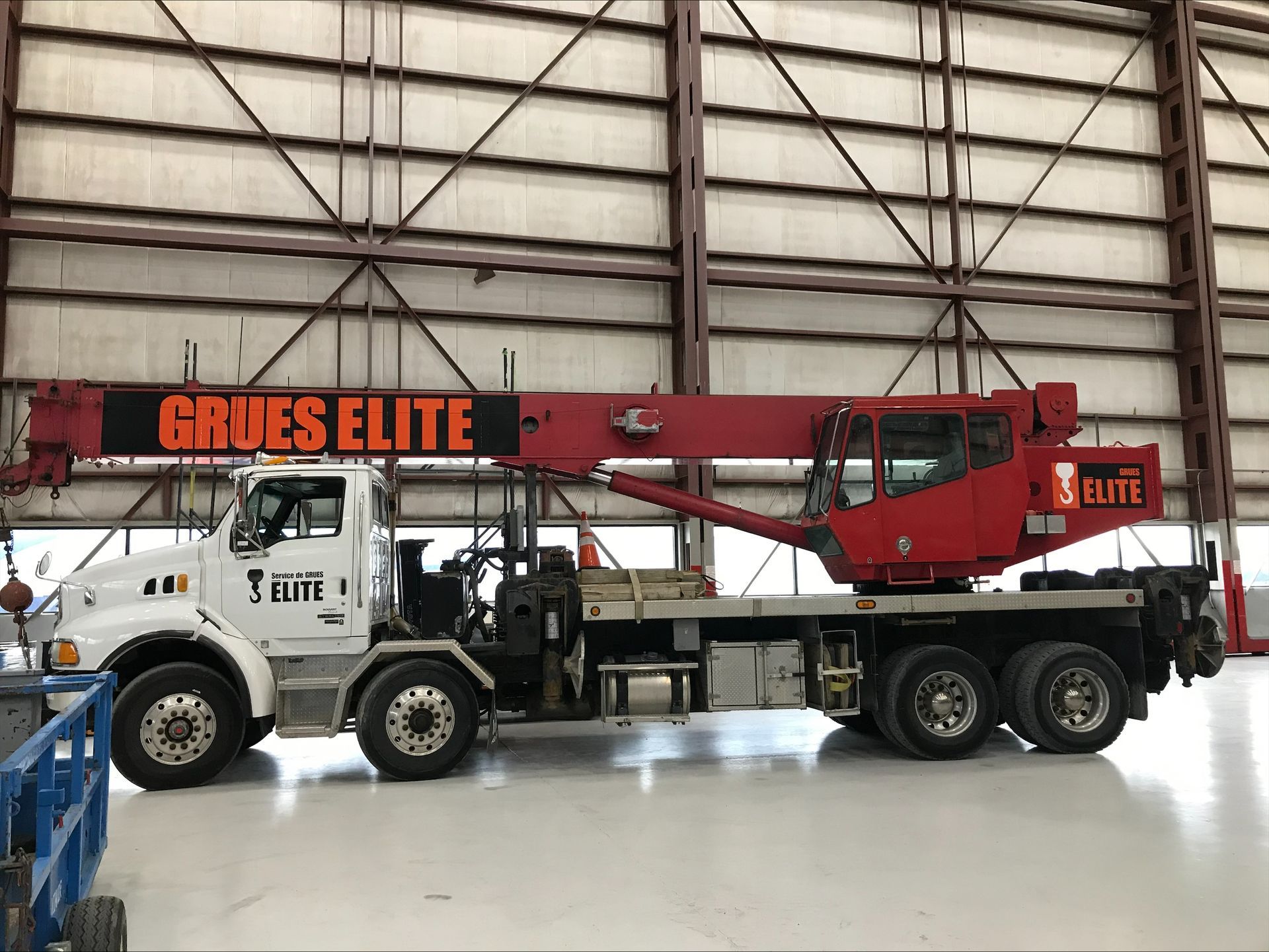 A red truck with a crane attached to it is parked in a hangar.