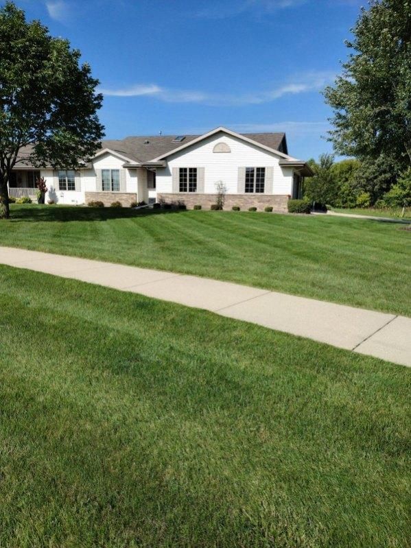 A house with a lush green lawn and a sidewalk in front of it.