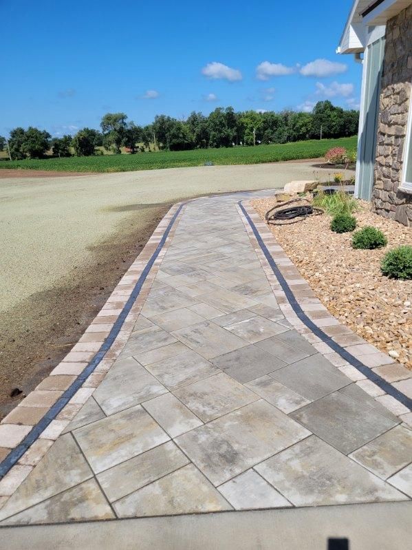 Finished custom paver walkway with decorative stone landscaping in Janesville, WI.