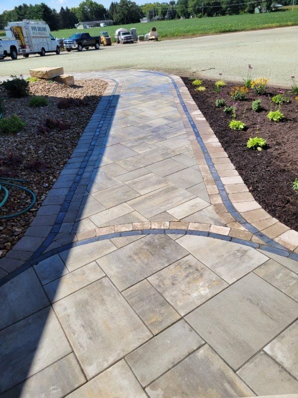 1. Completed paver walkway with curved borders, fresh landscaping, and planting beds in Janesville