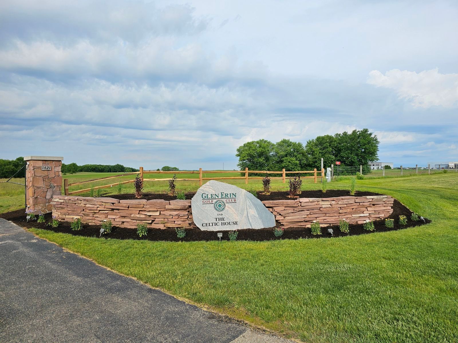 A brick wall surrounded by gravel next to a road.