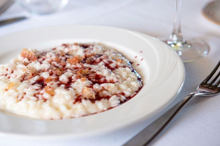 Piatto di cremoso budino di riso con salsa ai frutti di bosco su una tovaglia bianca.