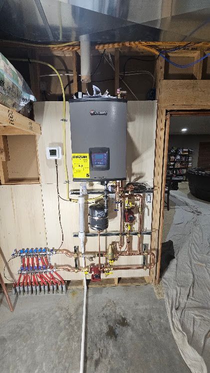 Basement utility room with wall-mounted boiler, pipes, valves, and electrical panels.