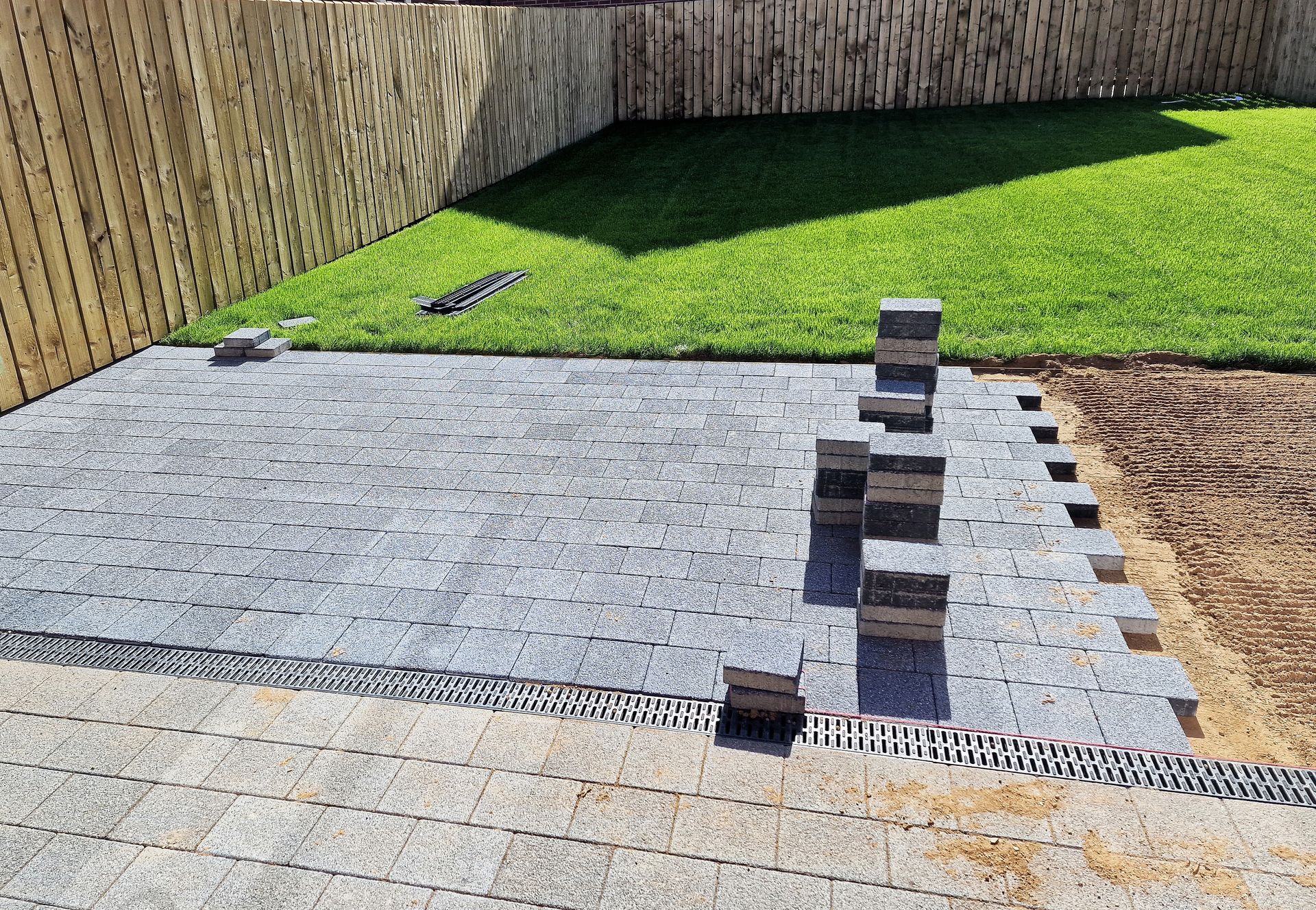Gray gravel patio under construction with black supports and green lawn background.
