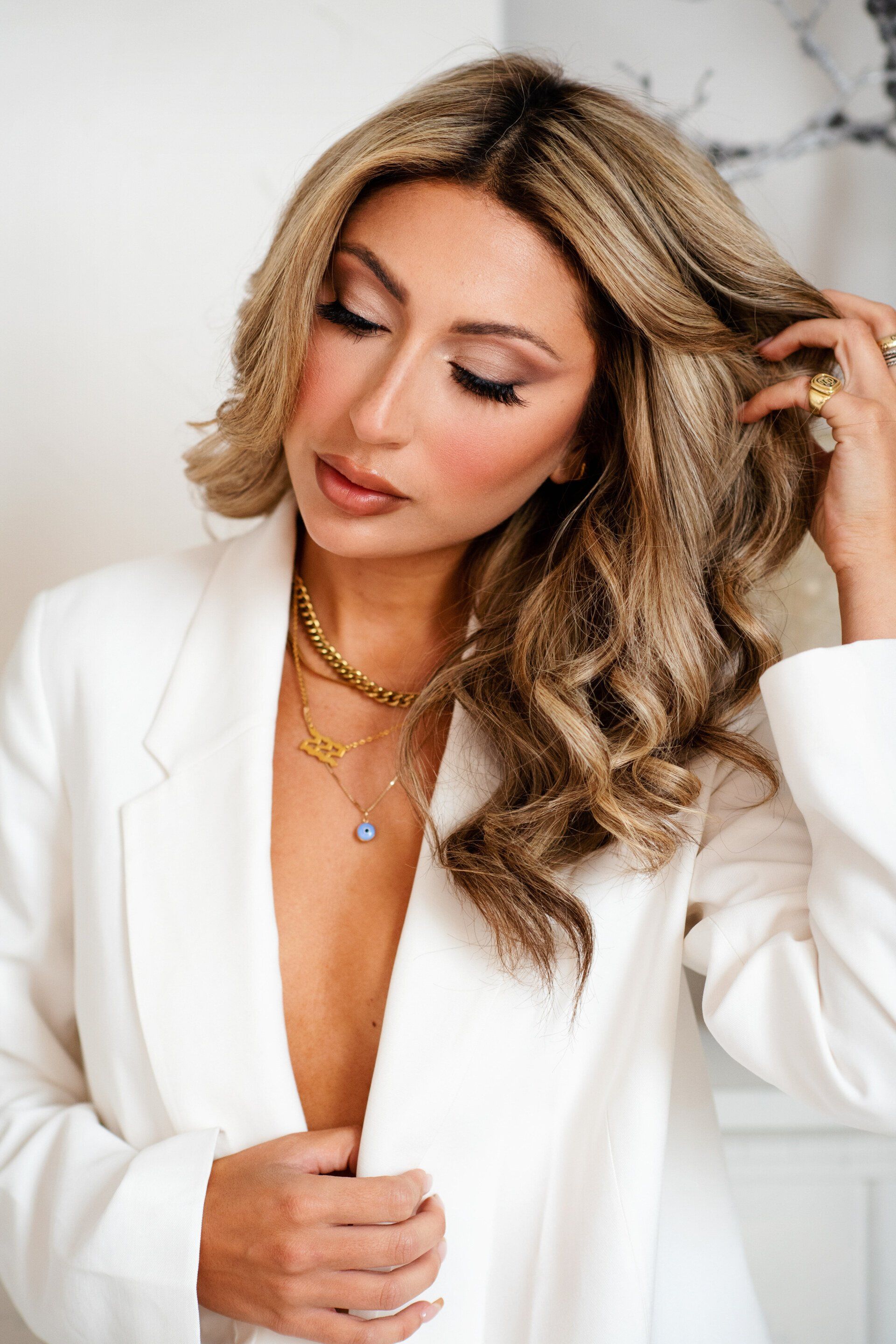 The woman is wearing a white jacket and a gold necklace.
