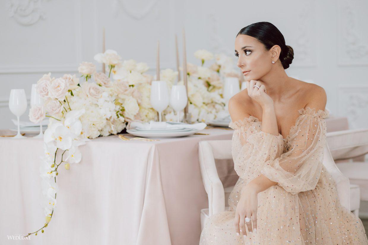 A woman in a wedding dress is sitting at a table with flowers.