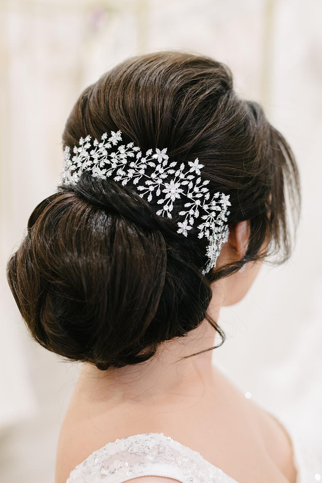 The bride is wearing a bun with a headpiece in her hair.