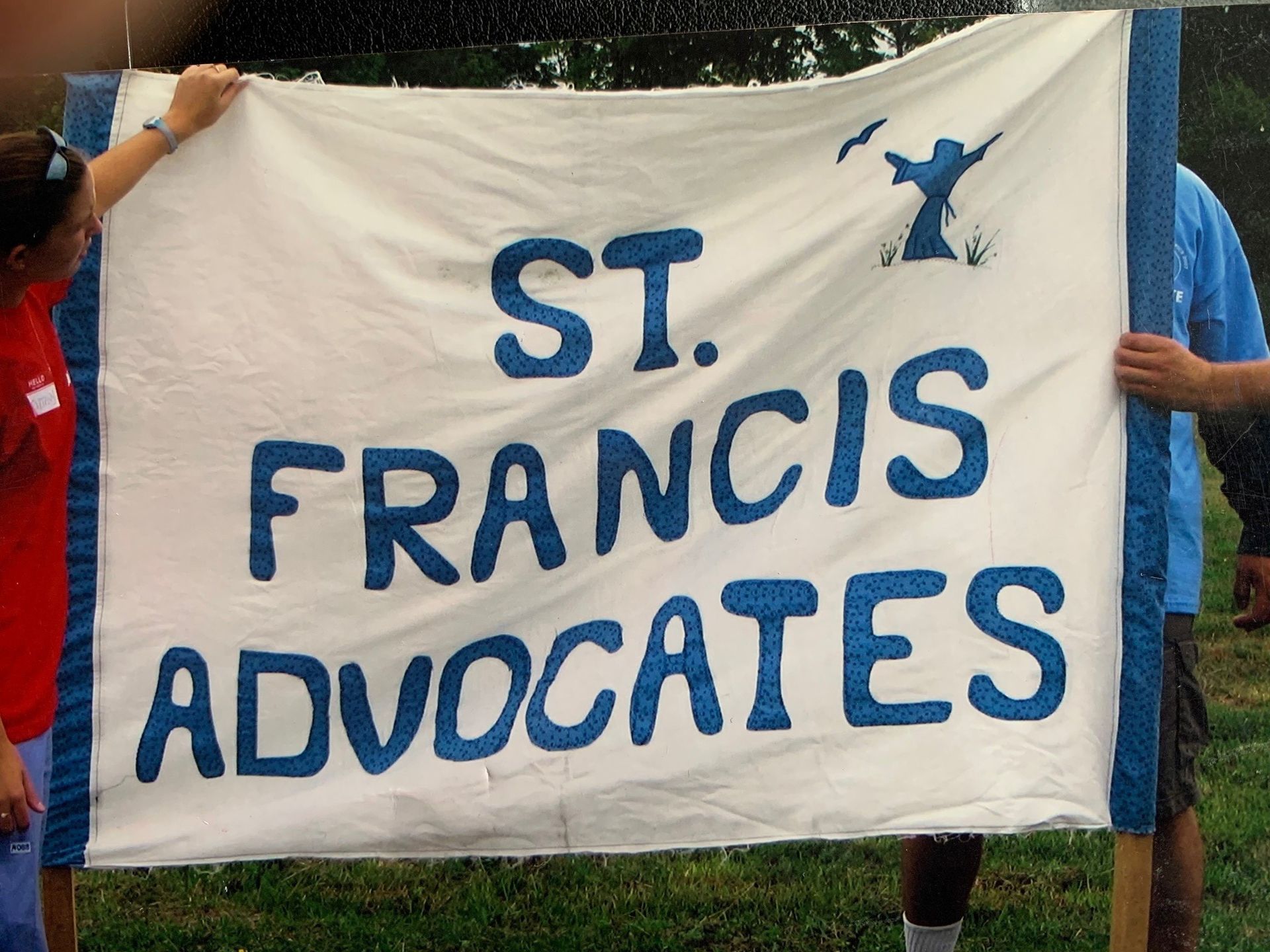 People holding a white banner with blue text: