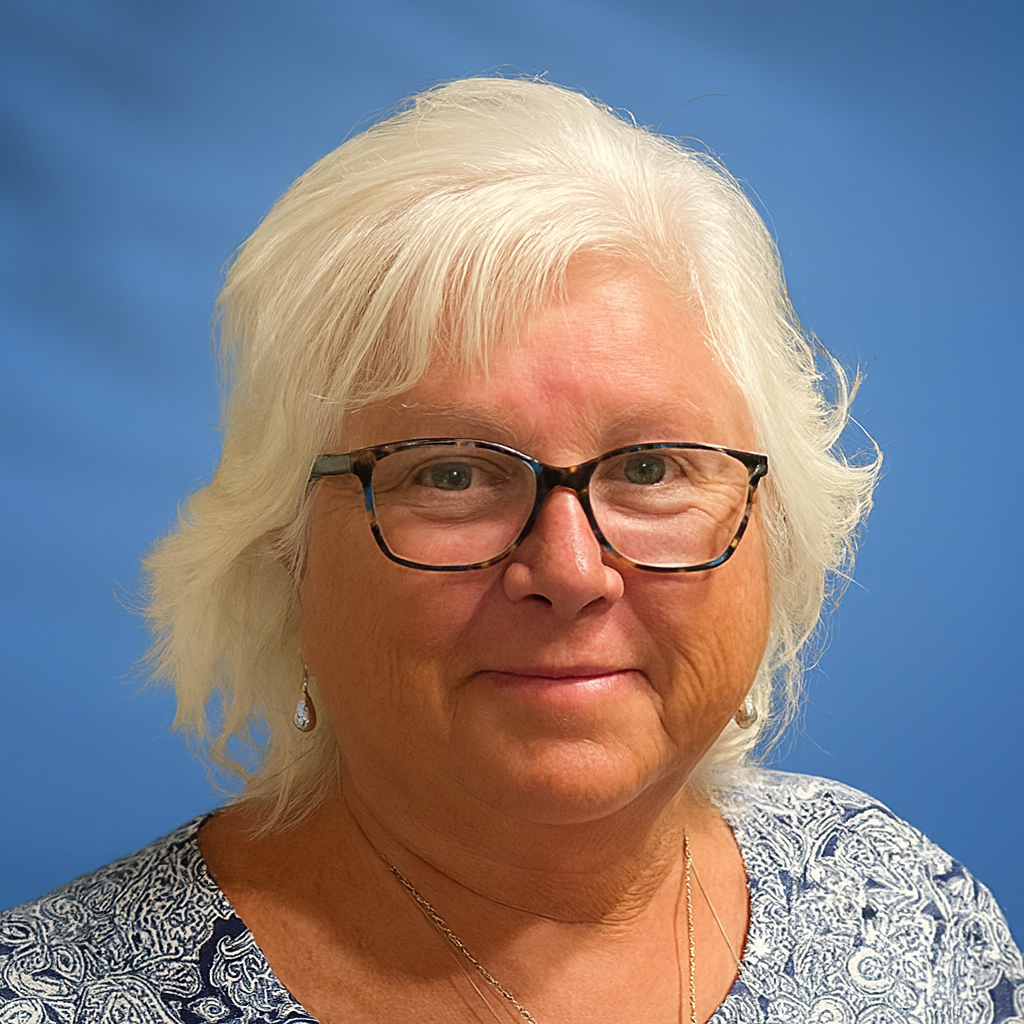 Woman with white hair and glasses smiles; blue patterned shirt, blue background.