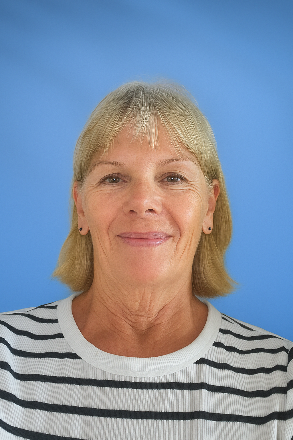 Woman with blonde hair wearing a striped shirt, smiling in front of a blue background.