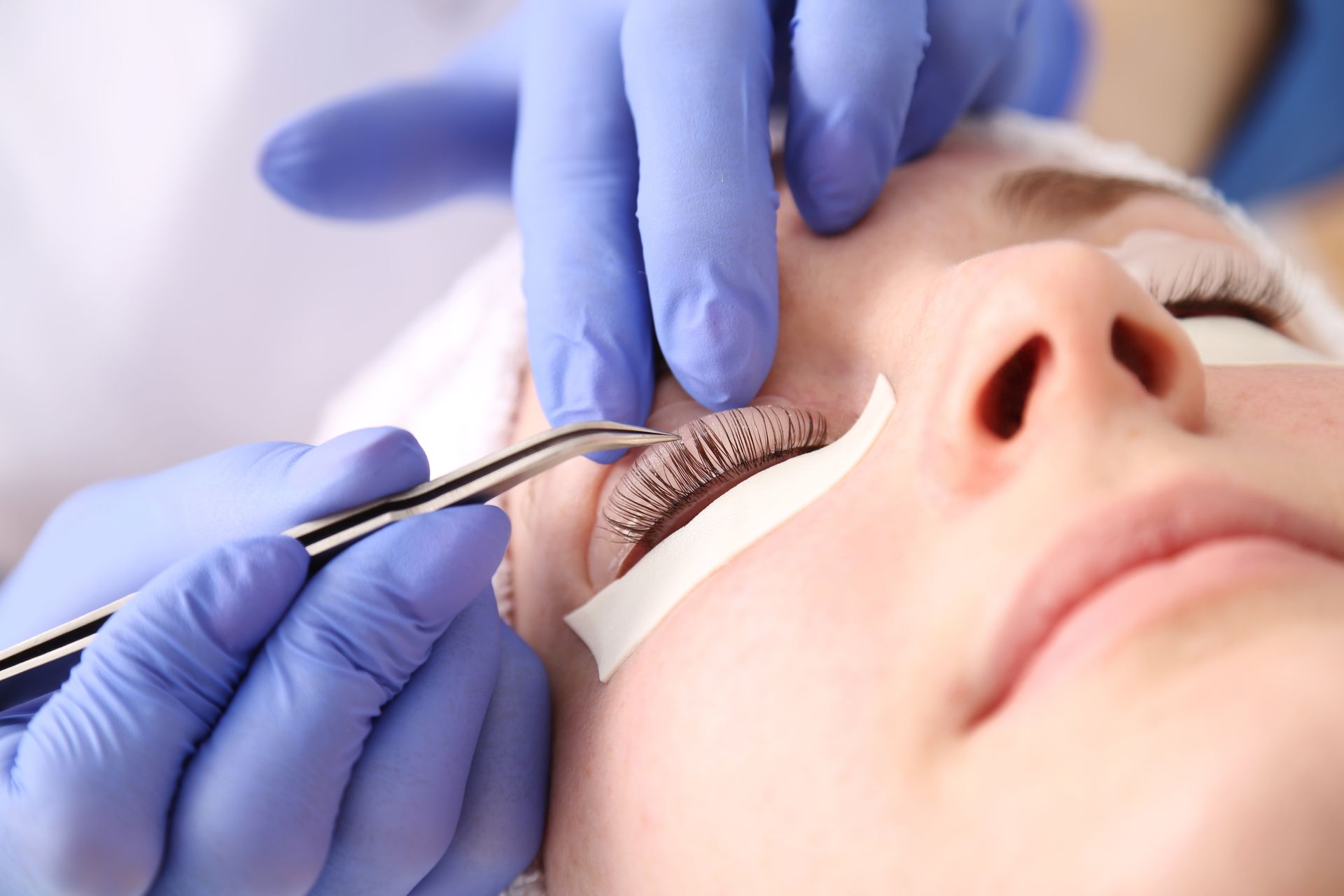 A woman is getting eyelash extensions in a beauty salon.