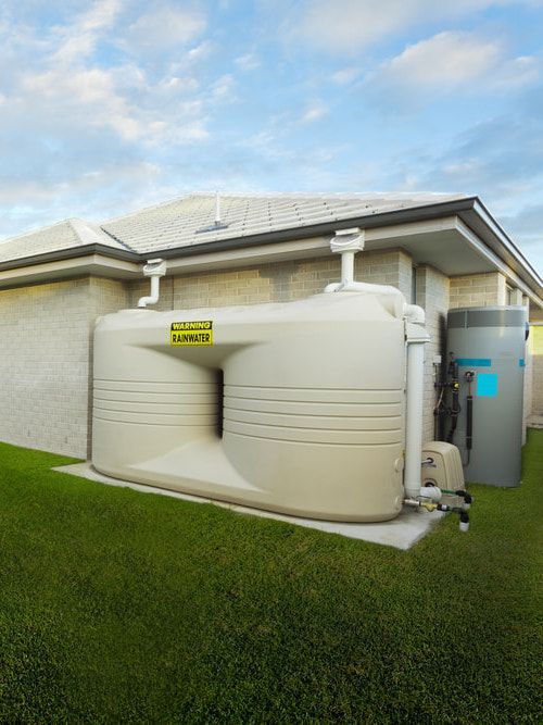 A Green Water Tank Is Sitting Next To A White Brick — Clear and Clean Water Tank Cleaning Services in Bridgman, NSW