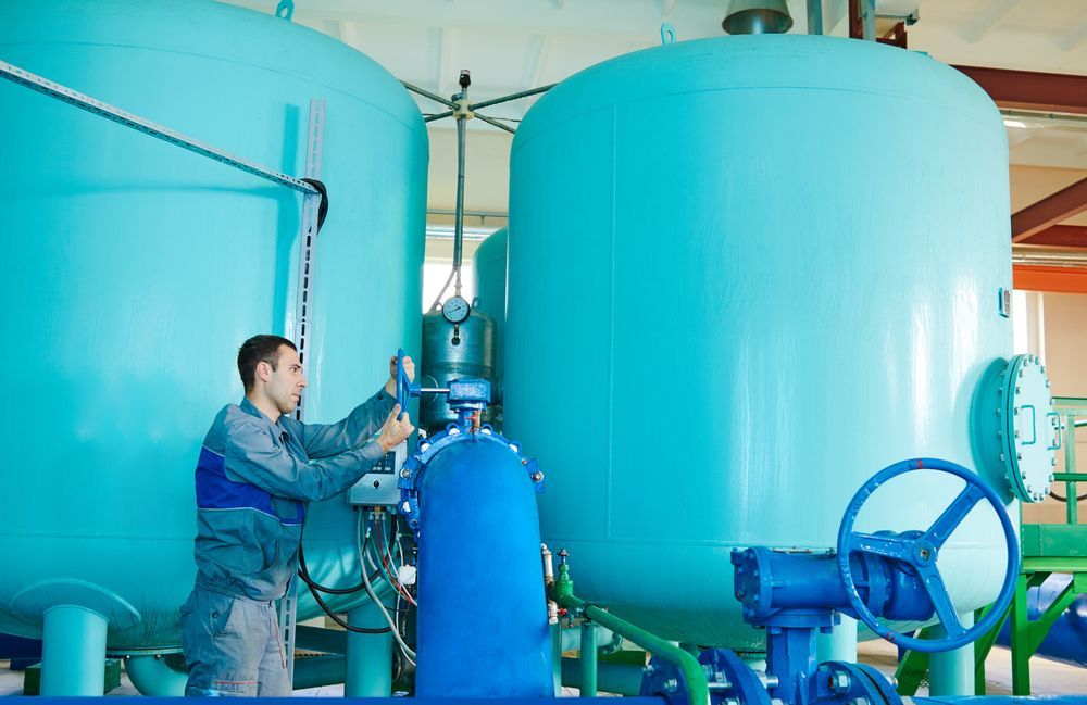 A Man Is Working On A Machine In A Factory — Clear and Clean Water Tank Cleaning Services in Scone, NSW