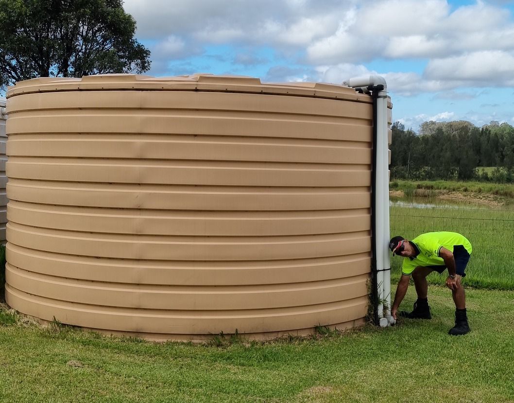 A Man In A Hard Hat Is Standing On A Ledge Looking At A Clipboard — Clear and Clean Water Tank Cleaning Services in Bridgman, NSW